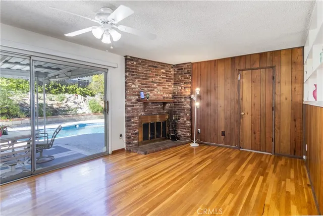 a view of an empty room with wooden floor and a fireplace