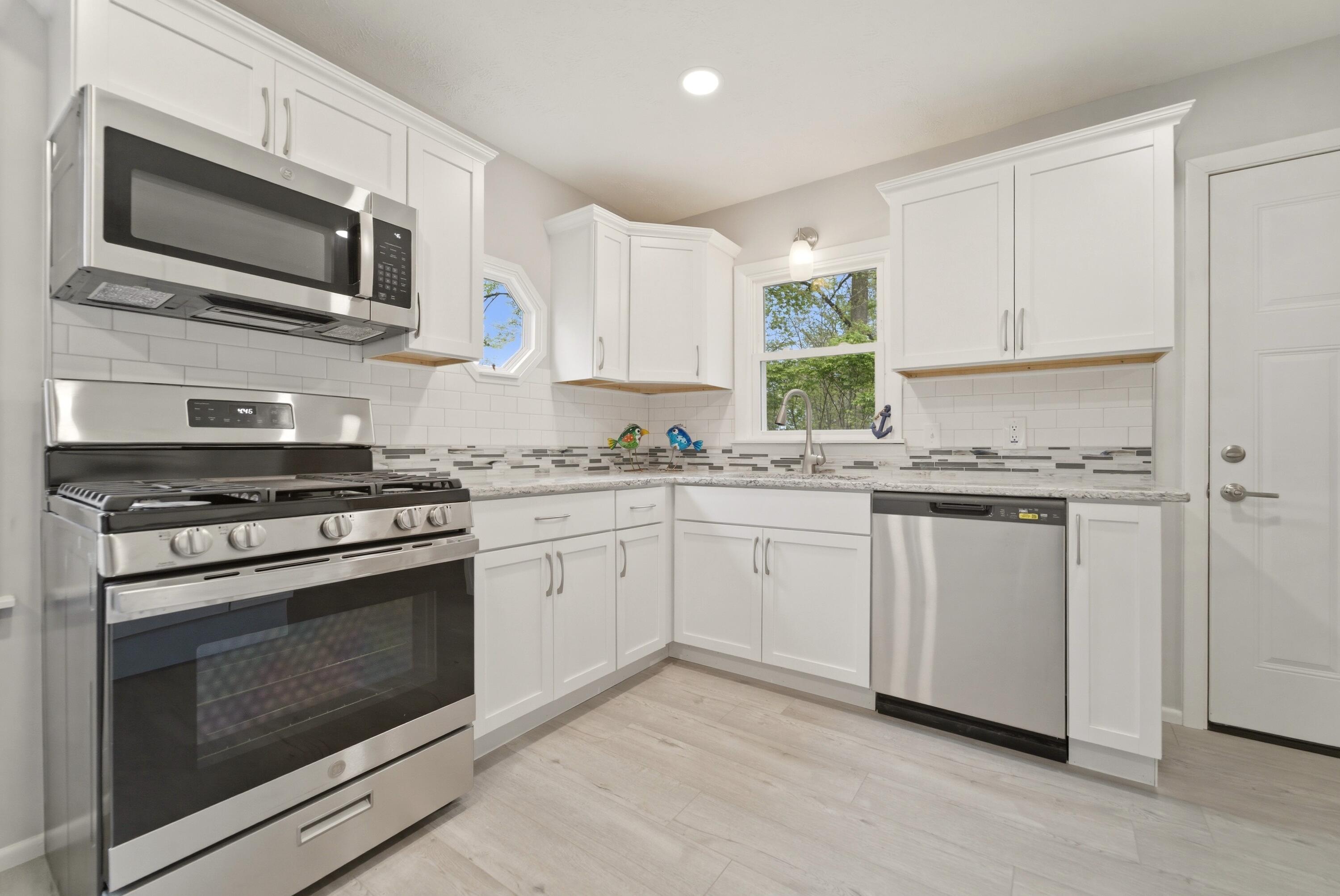 1208 Riley Court La Porte, IN 46350 - Photo 13 of 36 a kitchen with granite countertop white cabinets stainless steel appliances and window