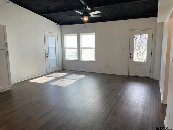an empty room with wooden floor and windows