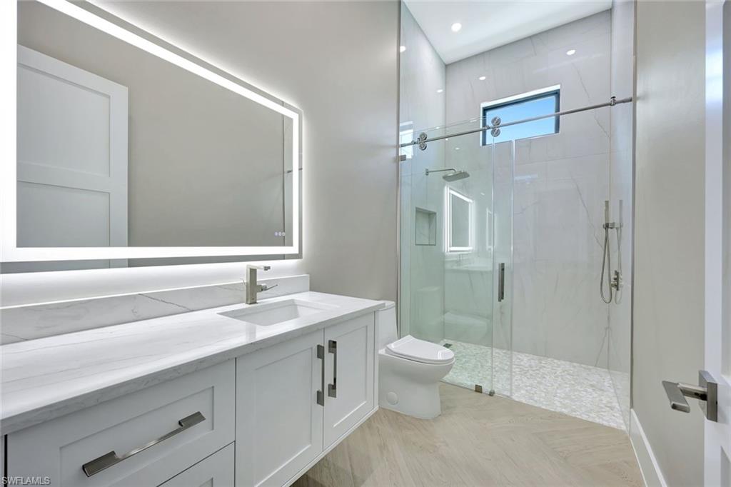 10493 Winterview Drive Naples, FL 34110 - Photo 17 of 40 a bathroom with a double vanity sink toilet and shower