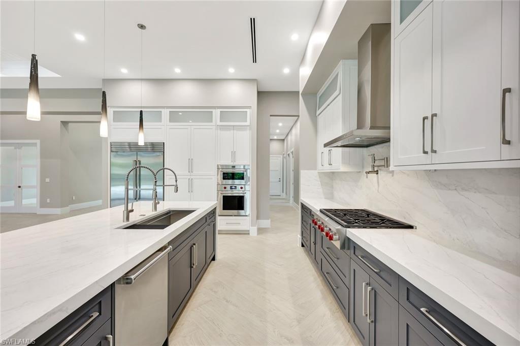 10493 Winterview Drive Naples, FL 34110 - Photo 8 of 40 a kitchen with kitchen island stainless steel appliances a sink stove and cabinets