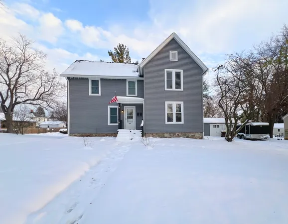a front view of a house with a yard covered in snow