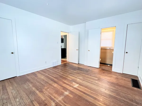 a view of an empty room with wooden floor and closet