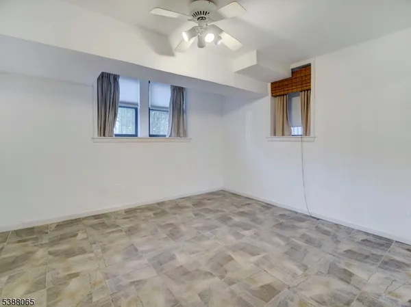 a view of an empty room with window and chandelier fan