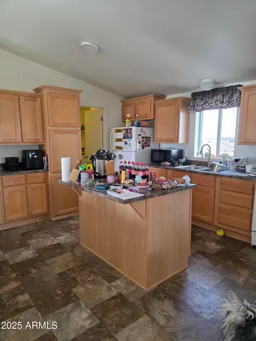 a kitchen with kitchen island granite countertop a sink counter top space and cabinets