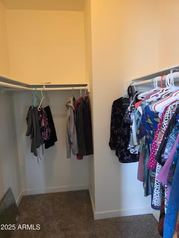a view of walk in closet with clothes and shoes