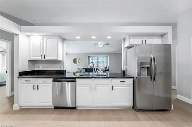 a kitchen with stainless steel appliances granite countertop a refrigerator a sink and white cabinets