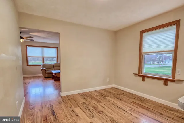 a view of empty room with wooden floor and a window