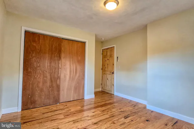 a view of an empty room with wooden floor and closet