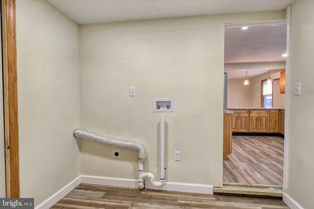 a view of a hallway with wooden floor and cabinet