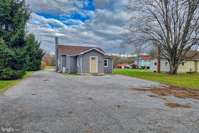 a view of house with a big yard and large trees