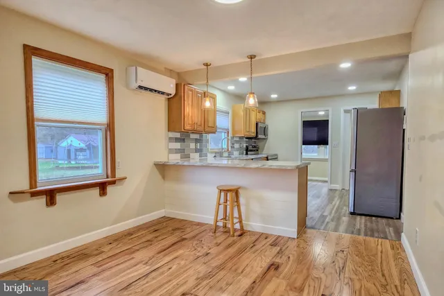 a kitchen with stainless steel appliances kitchen island granite countertop a refrigerator a stove a sink and a wooden floors