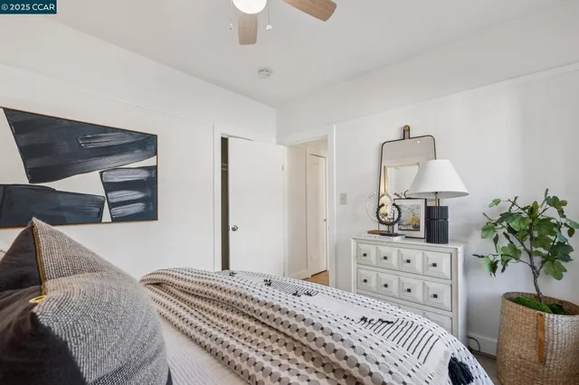 a bedroom with a bed and a potted plant on the dresser