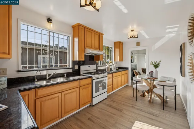 a kitchen with stainless steel appliances granite countertop wooden cabinets a sink dishwasher a stove and a refrigerator with wooden floor