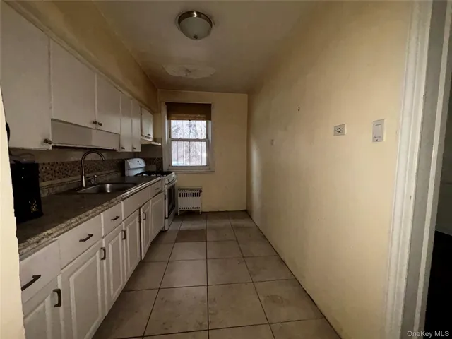 a kitchen with granite countertop white cabinets and window