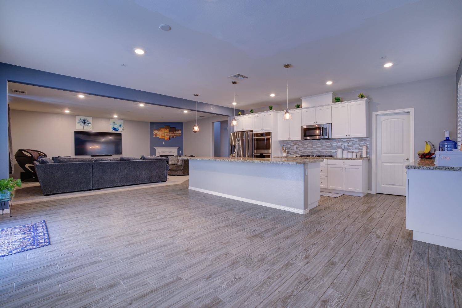26055 Plumcot Drive Corona, CA 92883 - Photo 25 of 47 a view of kitchen with kitchen island granite countertop a stove top oven a sink and a living room view