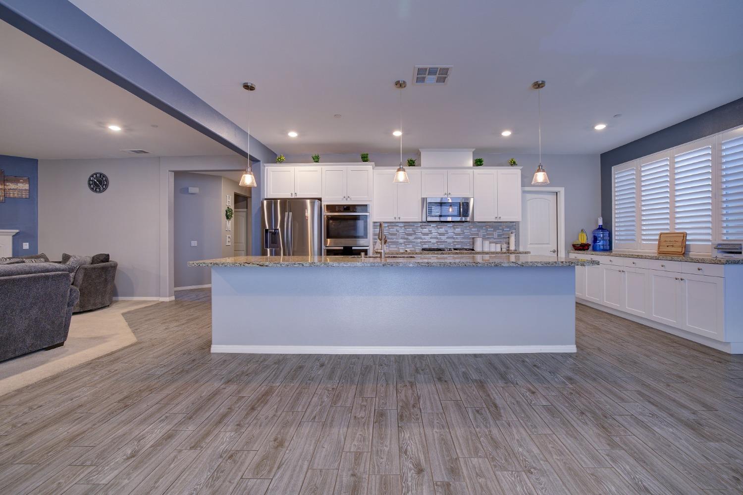 26055 Plumcot Drive Corona, CA 92883 - Photo 26 of 47 a large kitchen with stainless steel appliances granite countertop a large counter top a stove and a wooden floors