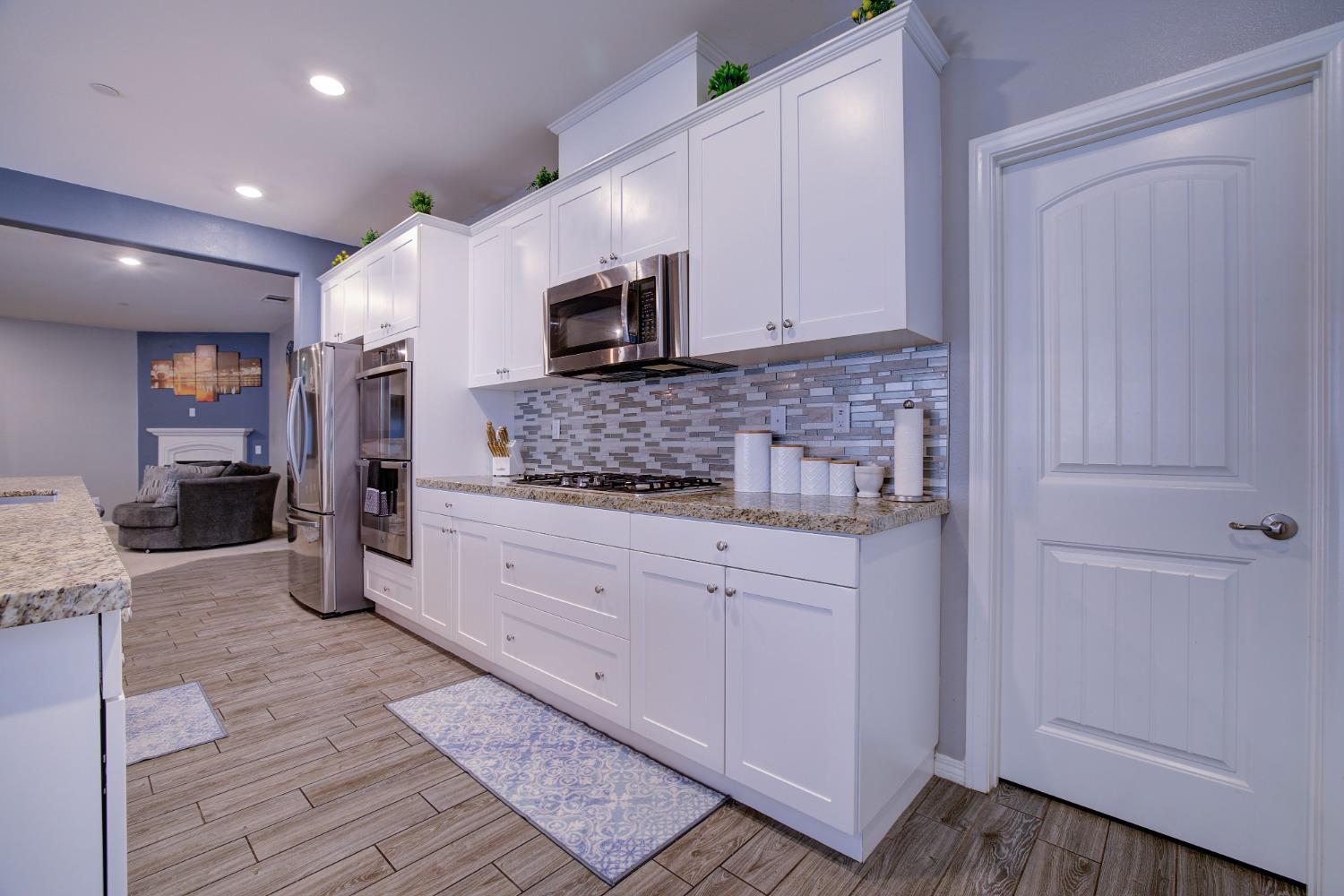 26055 Plumcot Drive Corona, CA 92883 - Photo 30 of 47 a kitchen with stainless steel appliances kitchen island granite countertop a refrigerator and microwave