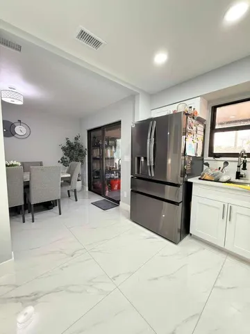 a kitchen with granite countertop a refrigerator and wooden cabinets