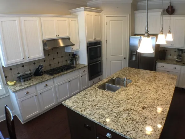 a kitchen with granite countertop a sink a stove and refrigerator