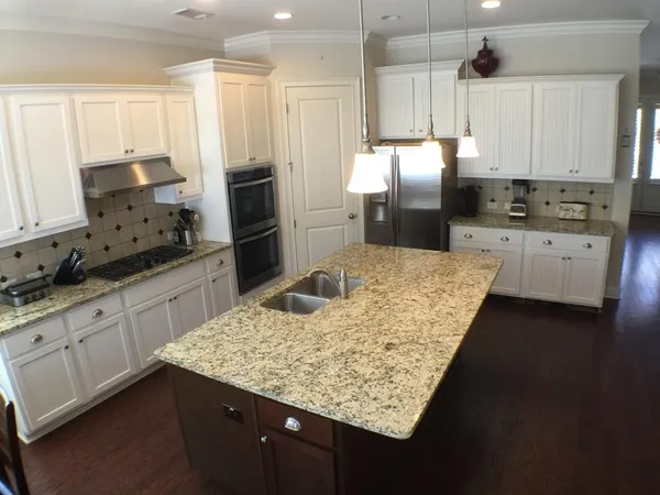 a kitchen with stainless steel appliances kitchen island granite countertop a sink refrigerator and cabinets