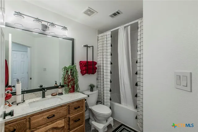 a bathroom with a granite countertop sink mirror vanity and toilet