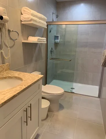 a bathroom with a granite countertop toilet a sink and shower