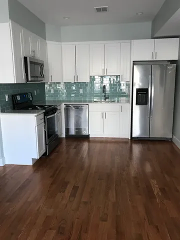 a kitchen with stainless steel appliances granite countertop a refrigerator a stove top oven a sink and dishwasher with wooden floor