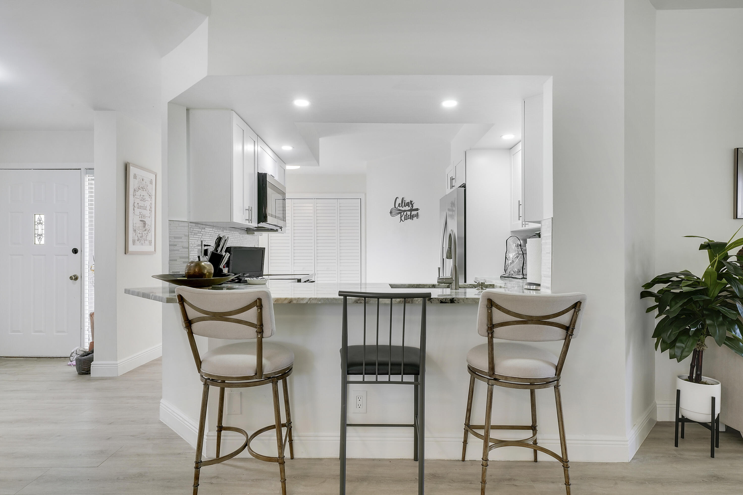 7860 Seville Place, Unit 2203 Boca Raton, FL 33433 - Photo 16 of 43 a kitchen with stainless steel appliances kitchen island a table chairs in it and wooden floors