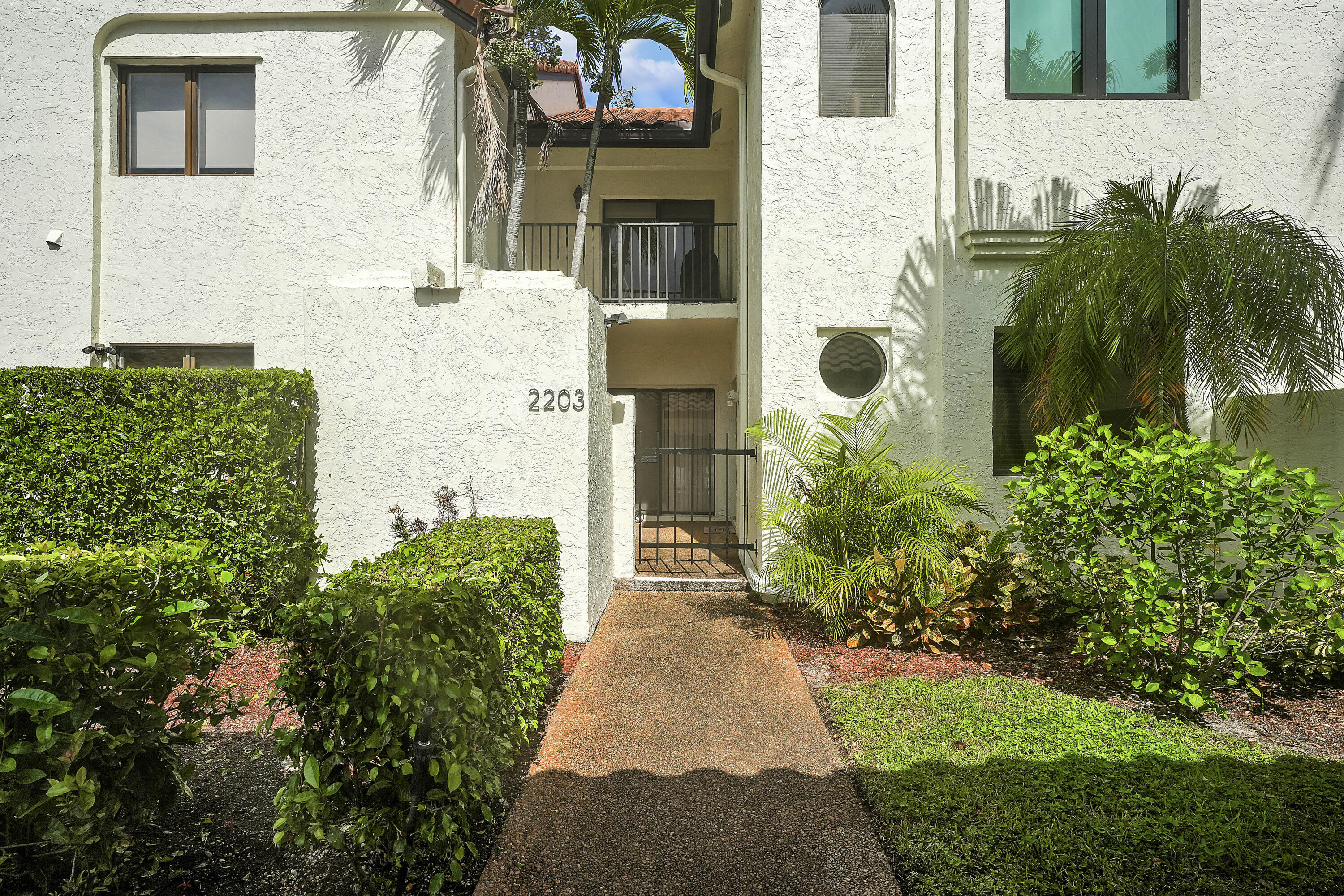 7860 Seville Place, Unit 2203 Boca Raton, FL 33433 - Photo 2 of 43 a front view of a house with a garden