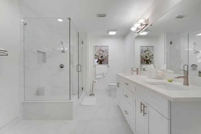 a bathroom with double vanity a toilet a and a sink