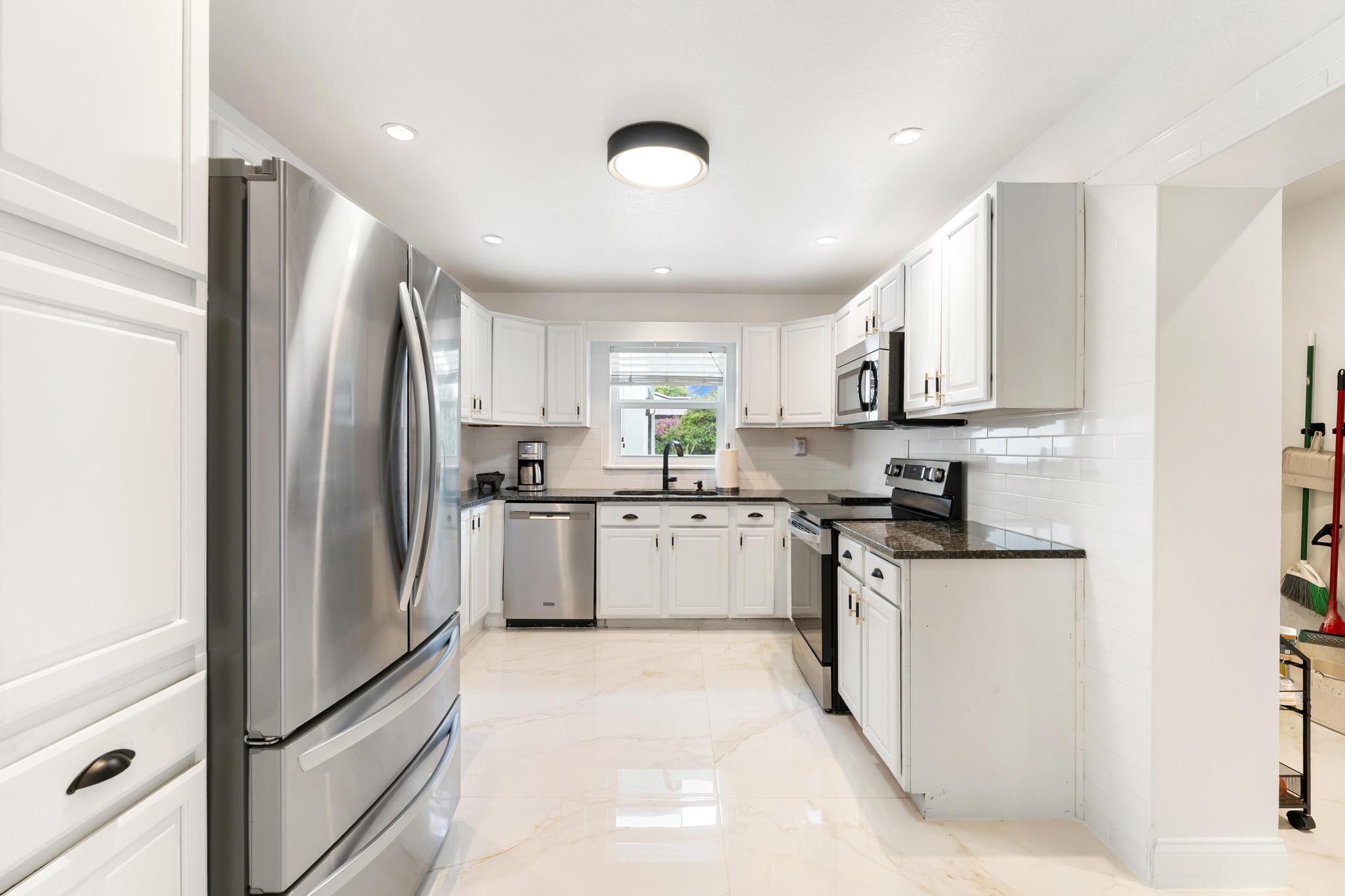 3179 Melaleuca Road West Palm Beach, FL 33406 - Photo 27 of 49 a kitchen with stainless steel appliances granite countertop a refrigerator sink and cabinets