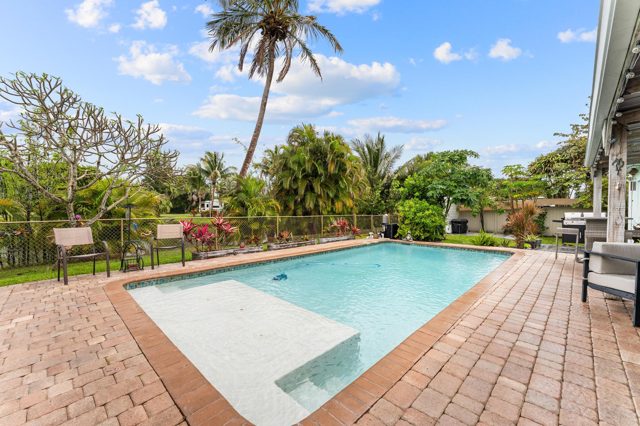 3179 Melaleuca Road West Palm Beach, FL 33406 - Photo 41 of 49 a view of a swimming pool with a chair and tables