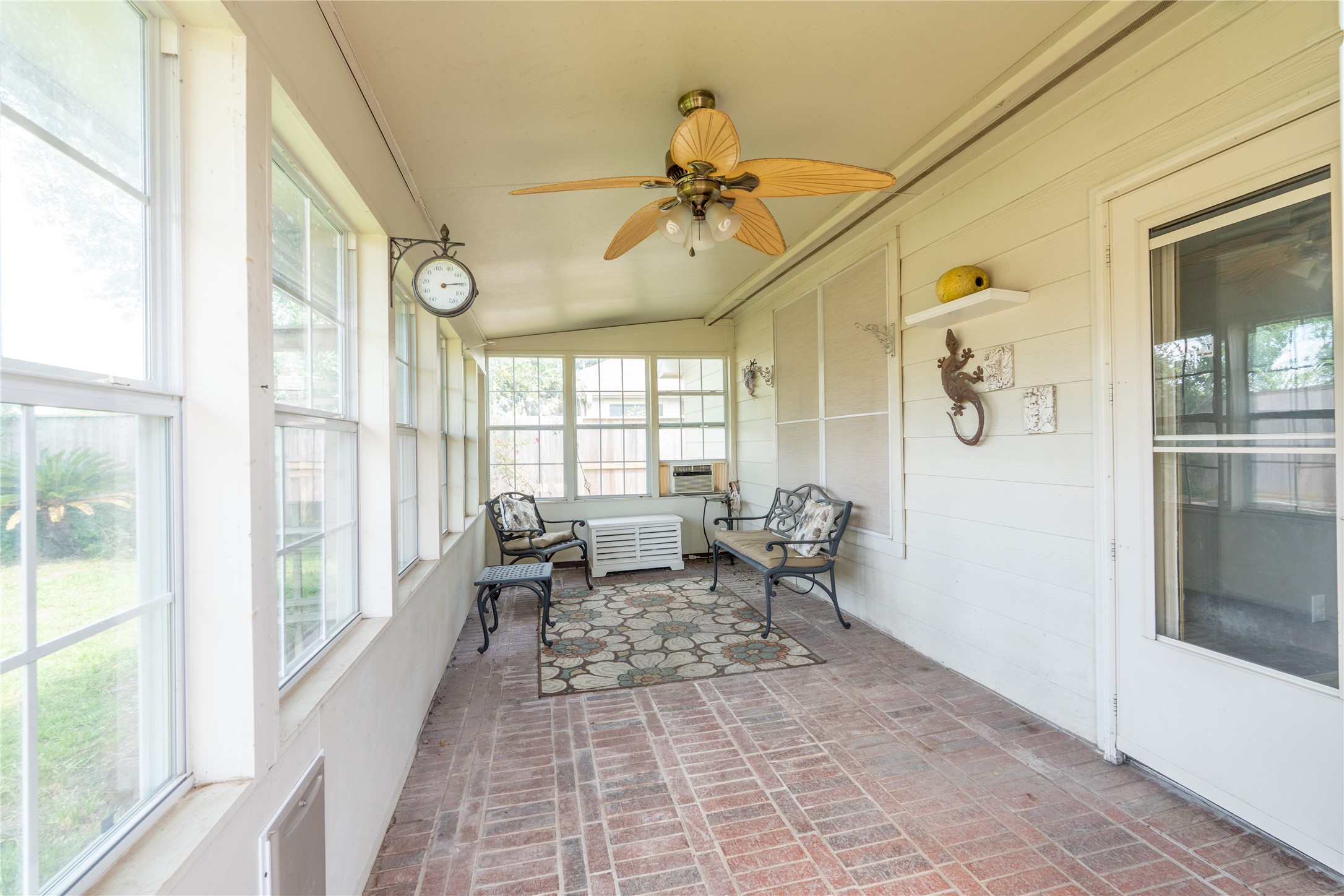 10619 Crownsedge Drive Spring, TX 77379 - Photo 30 of 38 This sunroom features large windows for abundant natural light, a ceiling fan for comfort, and a charming seating area with decorative elements, offering a cozy space to relax and enjoy the garden view.