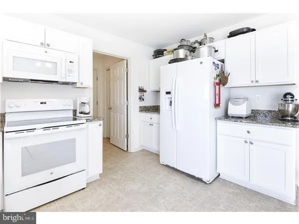 a kitchen with a refrigerator sink stove and white cabinets