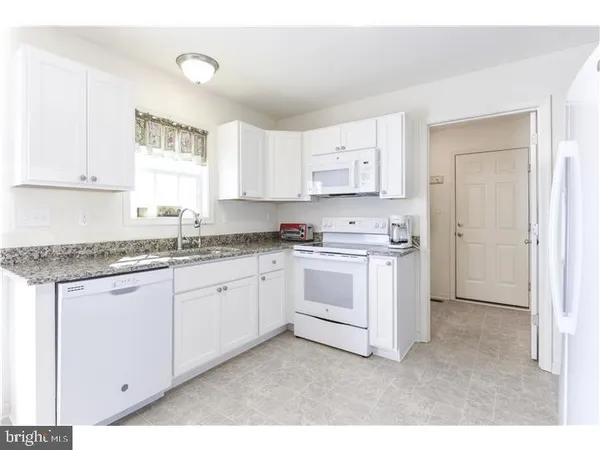 a kitchen with granite countertop white cabinets and white appliances