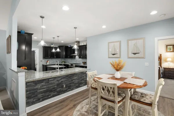 a kitchen with stainless steel appliances kitchen island granite countertop a table chairs and a refrigerator
