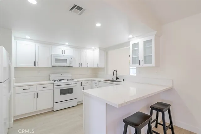 a kitchen that has a sink a stove and chairs