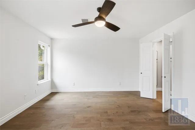 an empty room with windows and fan