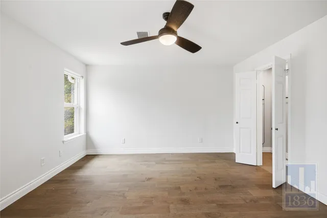 an empty room with windows and fan