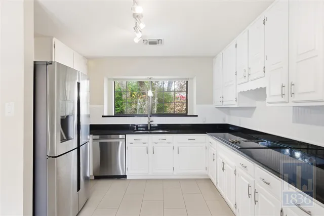 a large white kitchen with granite countertop a sink and dishwasher with a large window