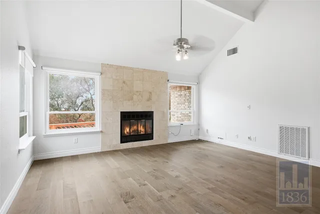 an empty room with windows fireplace and fans