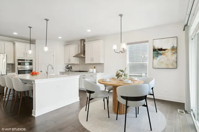 a kitchen with kitchen island granite countertop a table chairs a sink dishwasher window and cabinets