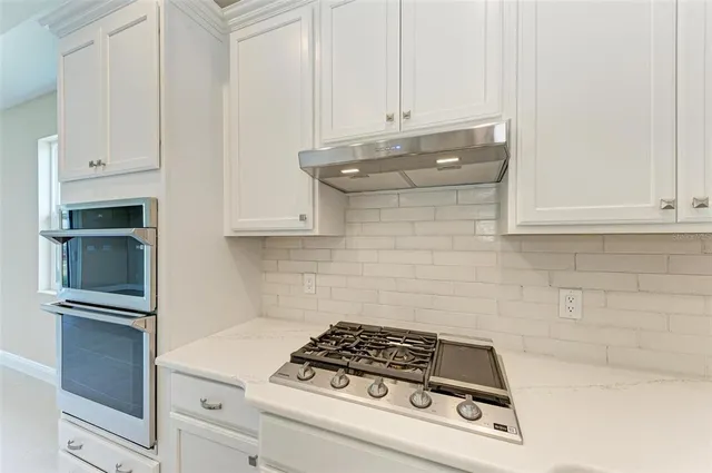 a kitchen with white cabinets and appliances
