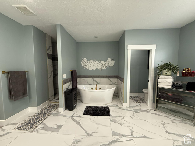 1240 West 2360 North Helper, UT 84526 - Photo 42 of 79 Full bath featuring a textured ceiling, visible vents, marble finish floor, toilet, and a freestanding bath