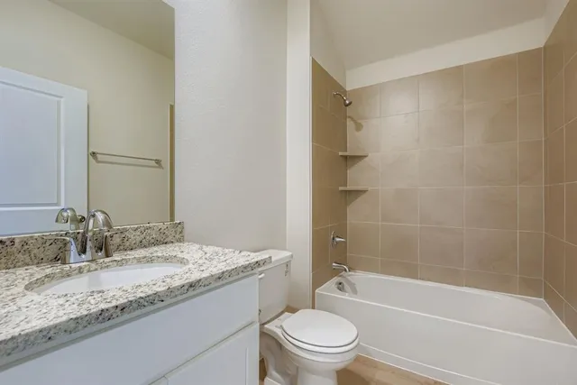 a bathroom with a granite countertop sink a toilet and shower