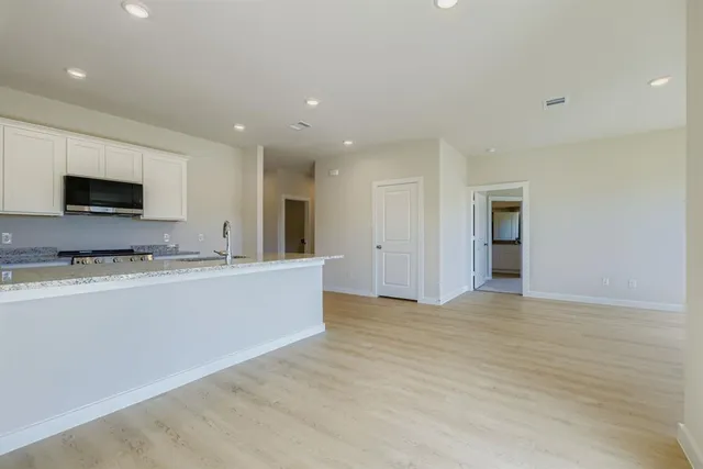 a view of kitchen with stainless steel appliances granite countertop cabinets and wooden floor