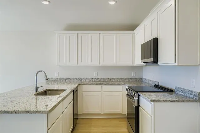 a kitchen with white cabinets sink and stove