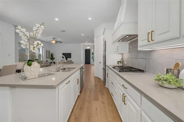 a kitchen with stainless steel appliances granite countertop a table chairs sink and cabinets