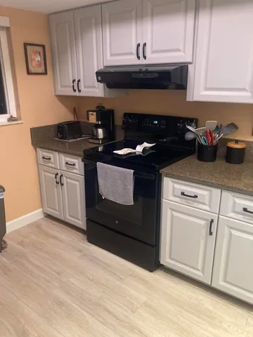 a kitchen with granite countertop white cabinets and black appliances
